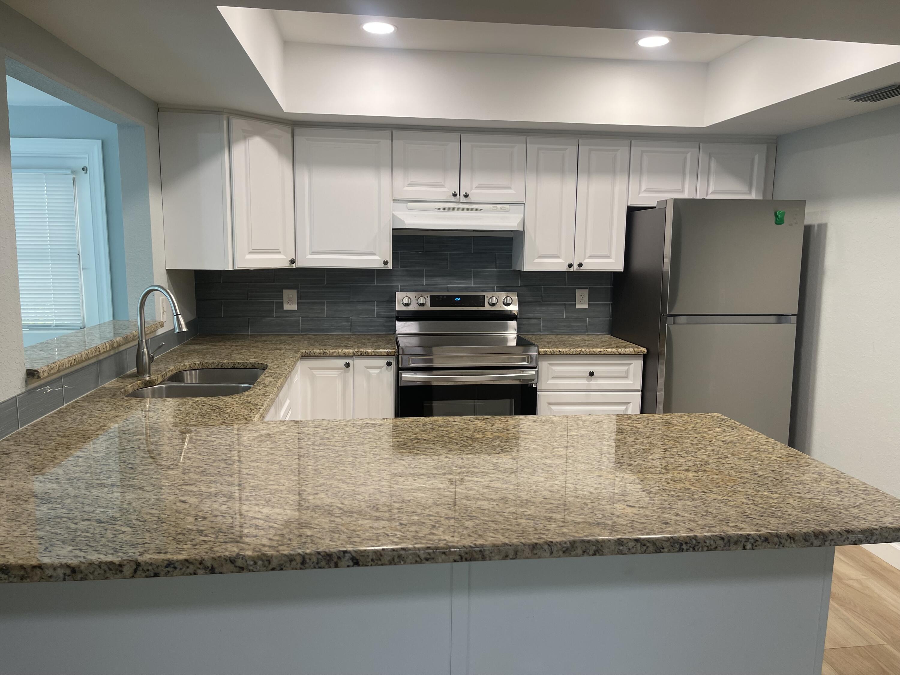 11737 Inverness Circle Wellington, FL 33414 - Photo 8 of 18 a kitchen with kitchen island granite countertop a stove a refrigerator and a sink