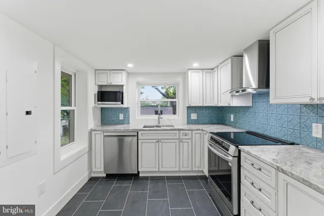 a kitchen with granite countertop white cabinets and stainless steel appliances