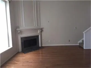 a view of a livingroom with wooden floor and a fireplace