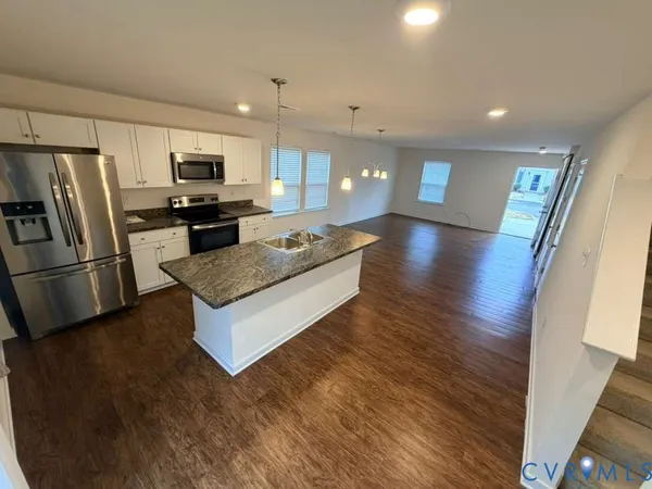 a large kitchen with stainless steel appliances a large counter top and a refrigerator