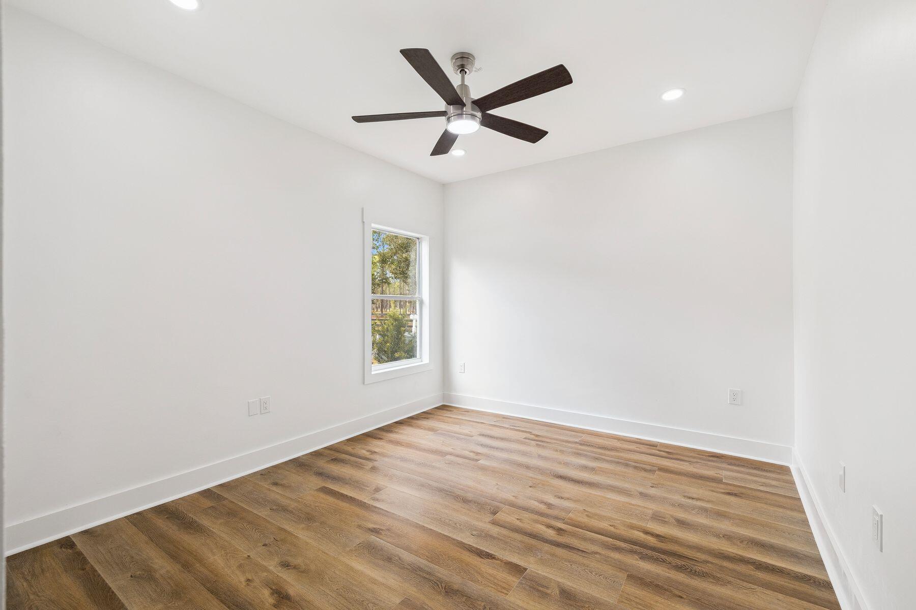 48 Pine Tree Way Santa Rosa Beach, FL 32459 - Photo 9 of 65 an empty room with wooden floor ceiling fan and windows