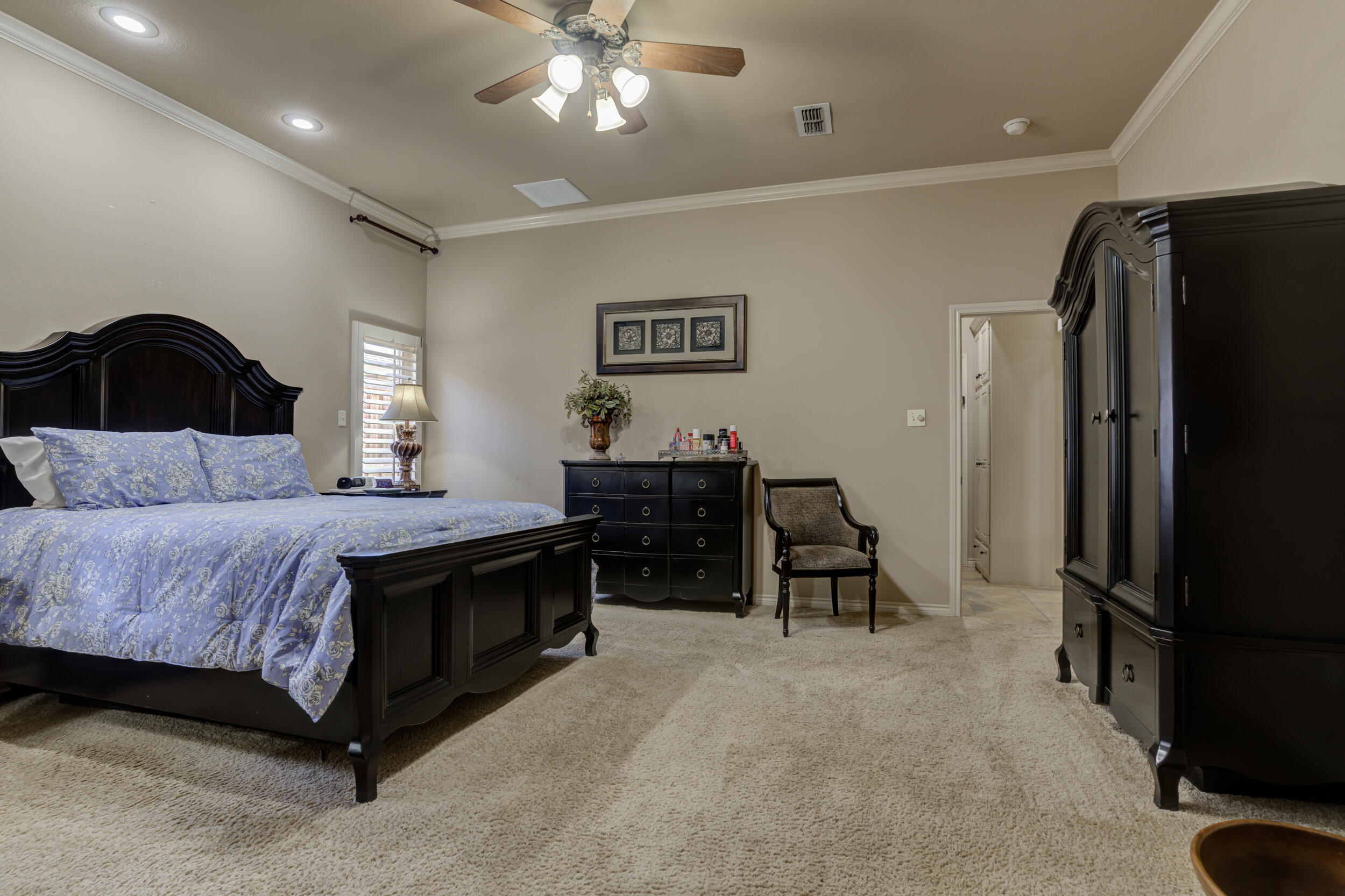 6008 89th Street Lubbock, TX 79424 - Photo 29 of 61 a spacious bedroom with a bed and a chandelier