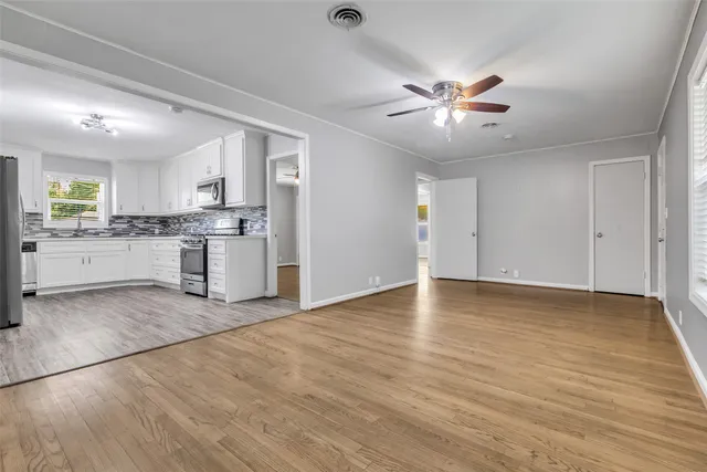 a view of a kitchen with a stove cabinets a ceiling fan and wooden floor
