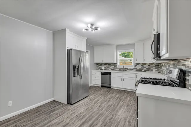 a kitchen with granite countertop a refrigerator and a stove top oven