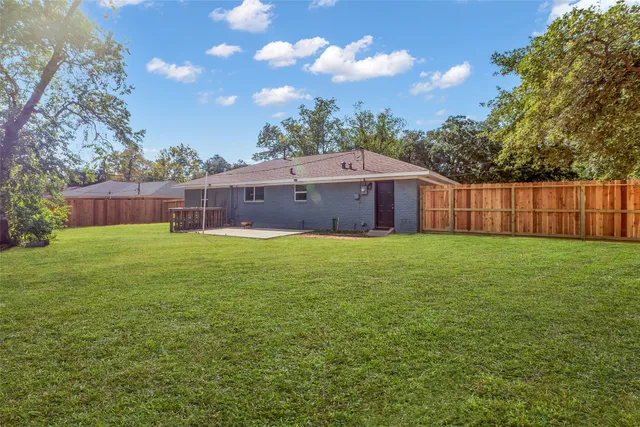 a view of a house with a yard and a large tree