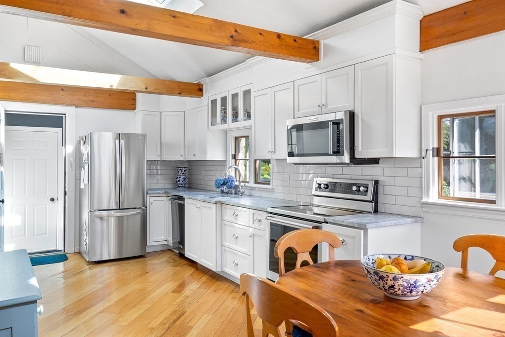 11 Lawson Road Scituate, MA 02066 - Photo 8 of 33 a kitchen with stainless steel appliances granite countertop a stove top oven a sink dishwasher a dining table and chairs with wooden floor