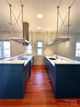 a large kitchen with kitchen island a sink wooden floor and a large window