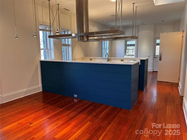 a kitchen with kitchen island wooden floors and stainless steel appliances