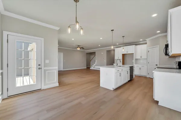 a large kitchen with kitchen island a stove a sink a center island and wooden floor