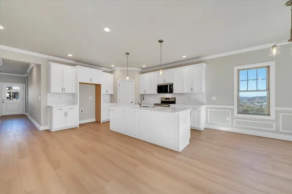 a view of kitchen with stainless steel appliances kitchen island wooden floors and white cabinets