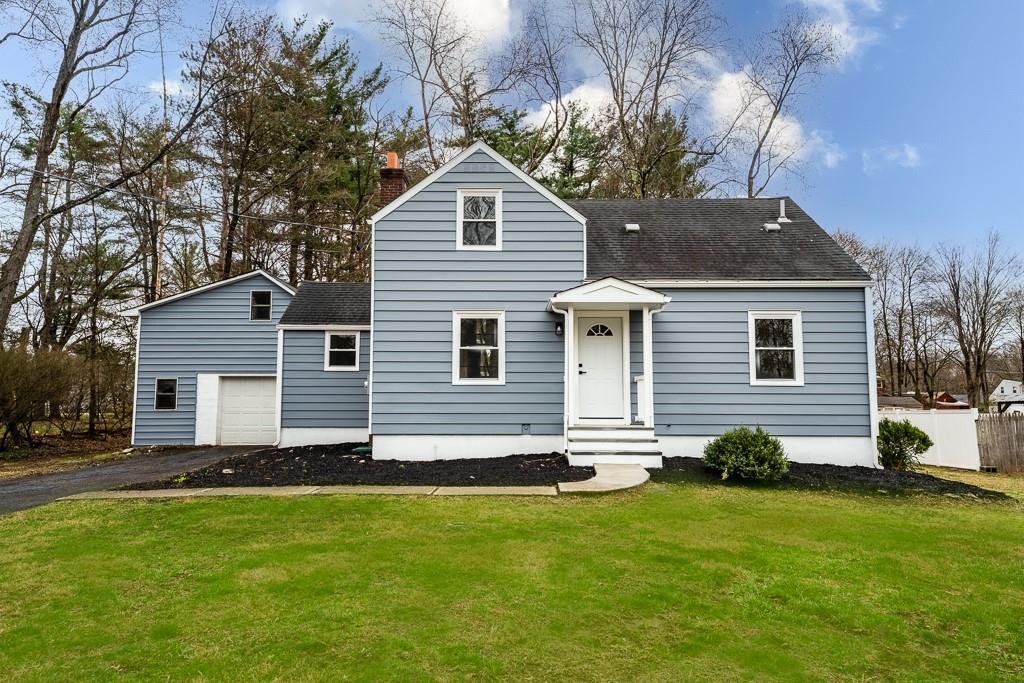 a front view of house with yard and trees in the background