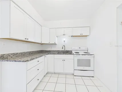 a kitchen with granite countertop white cabinets and white appliances