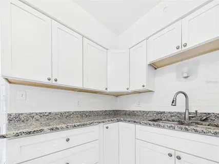a kitchen with granite countertop white cabinets and sink