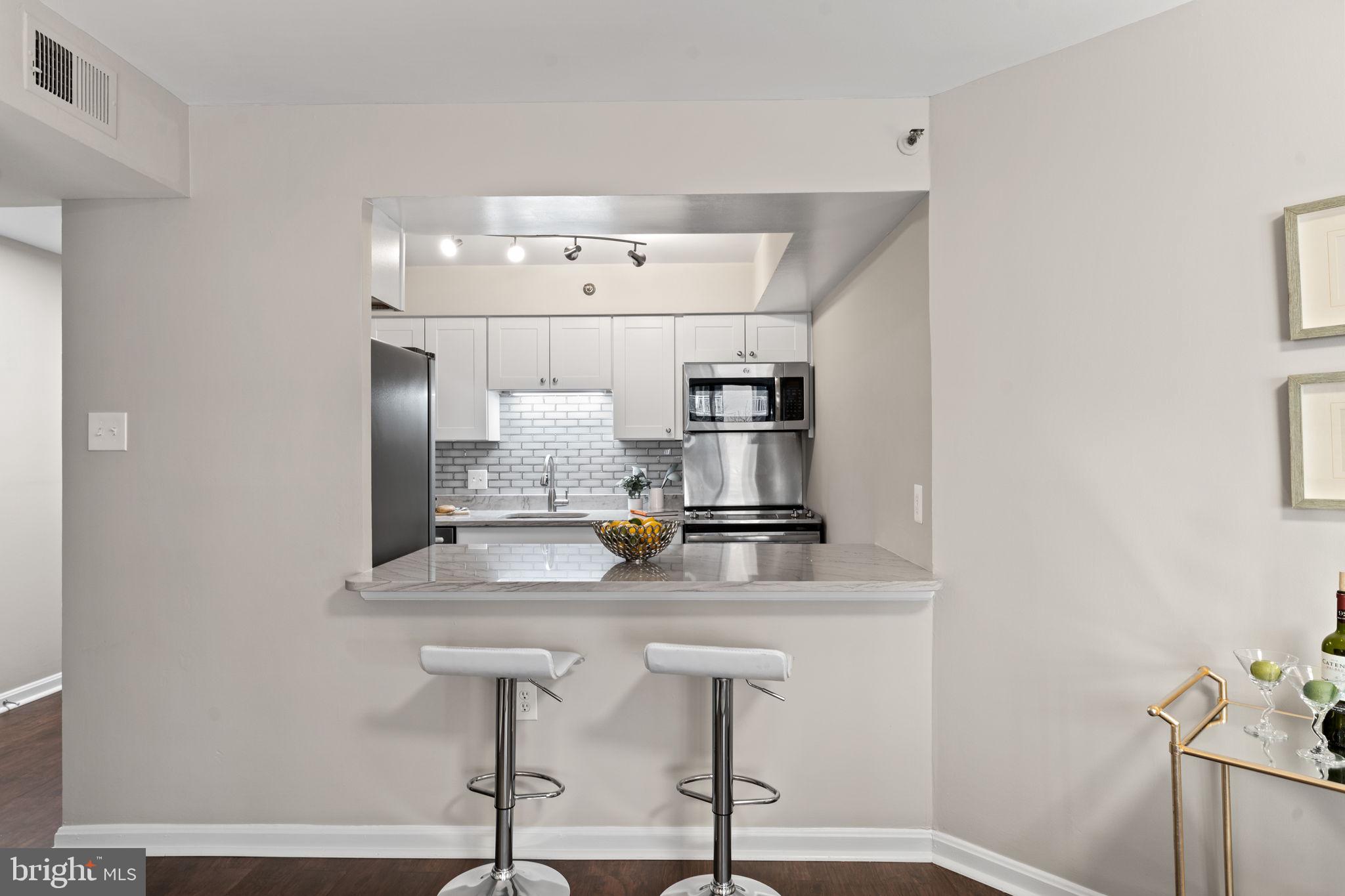 1301 North Courthouse Road, Unit 914 Arlington, VA 22201 - Photo 12 of 50 a kitchen with kitchen island stainless steel appliances a sink cabinets and wooden floor
