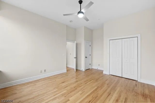 a view of a room with wooden floor and a ceiling fan