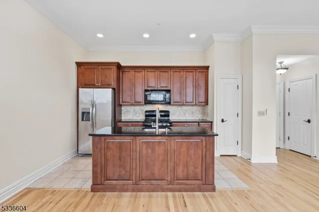 a kitchen with stainless steel appliances granite countertop a stove a sink and a refrigerator with wooden floor