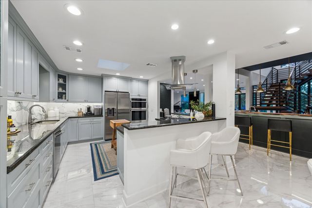 a kitchen with stainless steel appliances kitchen island granite countertop a sink and a stove