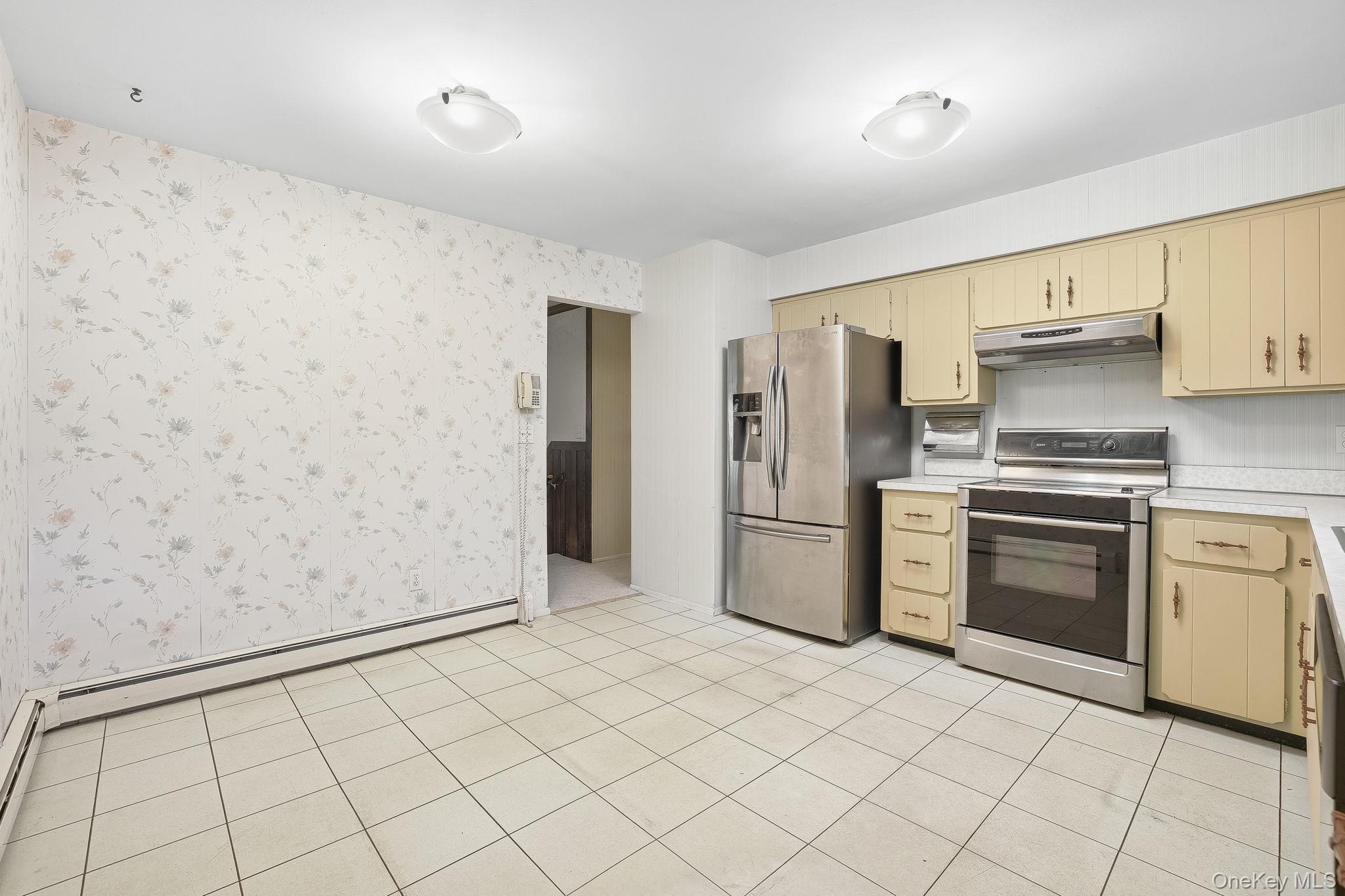 42 Bayberry Hill Road Mahopac, NY 10541 - Photo 11 of 49 Kitchen with light countertops, appliances with stainless steel finishes, a baseboard heating unit, wallpapered walls, and under cabinet range hood