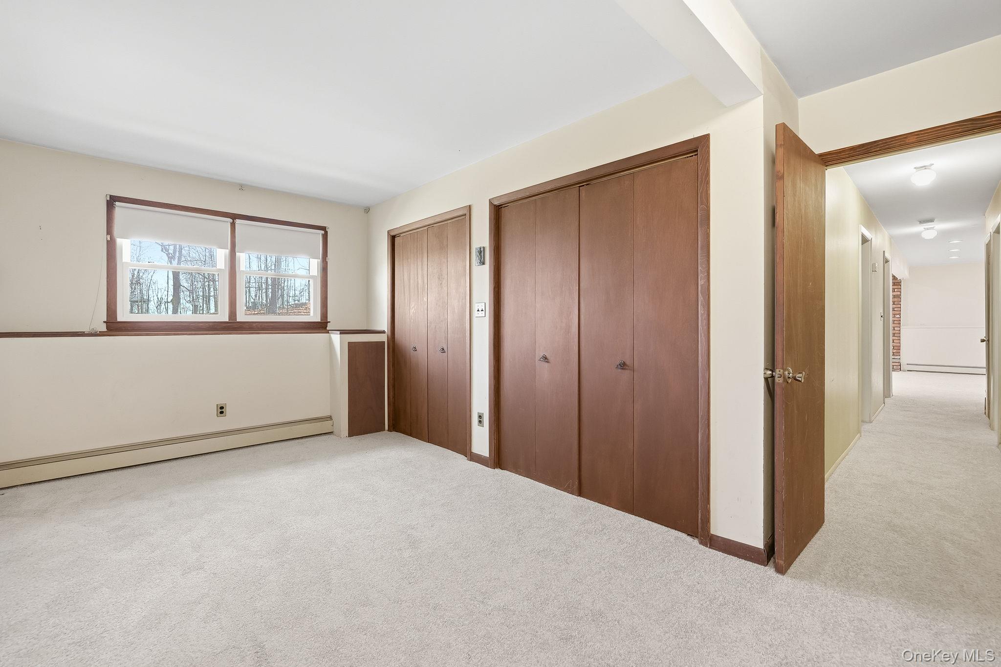 42 Bayberry Hill Road Mahopac, NY 10541 - Photo 28 of 49 Unfurnished bedroom featuring multiple closets, light colored carpet, and a baseboard radiator