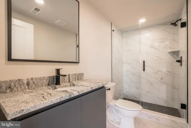 a bathroom with a granite countertop sink toilet and shower