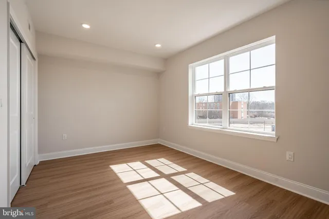 an empty room with wooden floor and windows