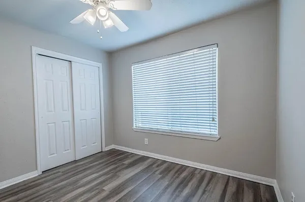 an empty room with wooden floor ceiling fan and windows
