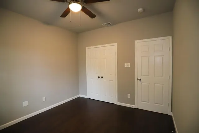 an empty room with a ceiling fan and wooden floor