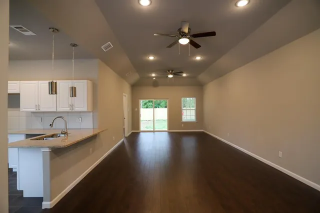 a view of an empty room with window and wooden floor