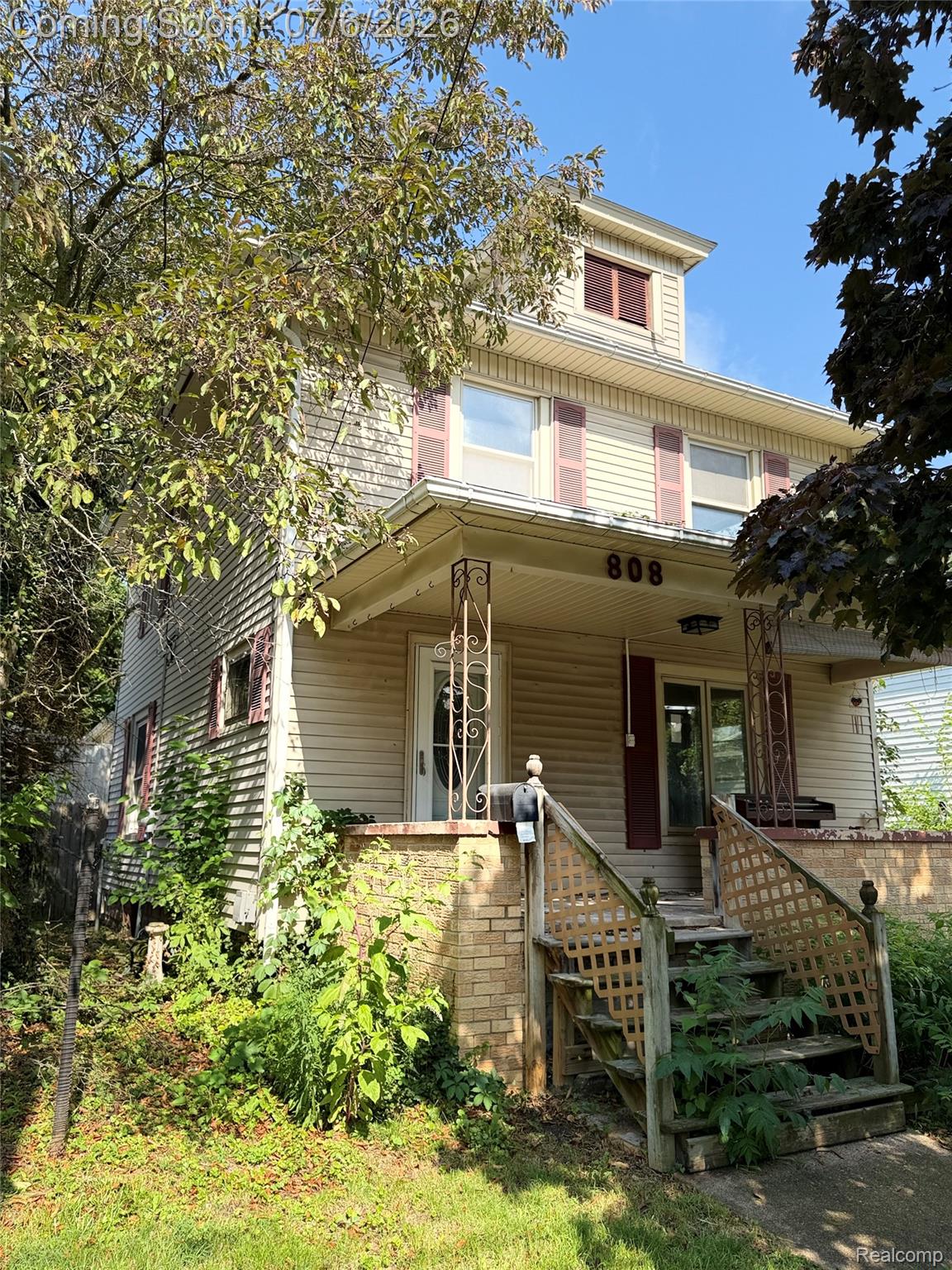 808 Division Street Owosso, MI 48867 - Photo 2 of 25 Two-story residence featuring light-colored siding, a covered front porch with decorative iron columns, and a dormer window