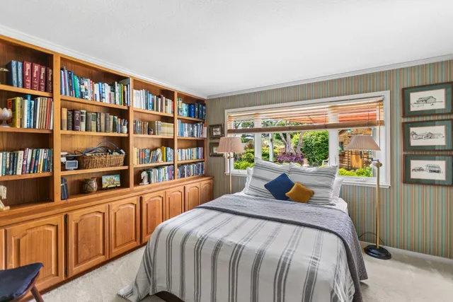 a bedroom with a bed a large window and a book shelf