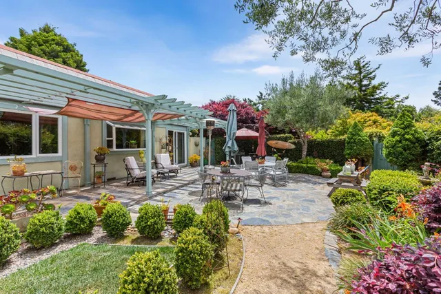 a view of a patio with table and chairs potted plants and large tree