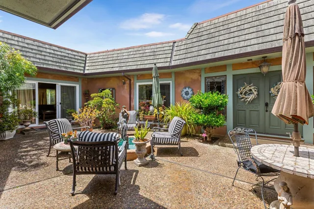 a view of a patio with a dining table and chairs and potted plants