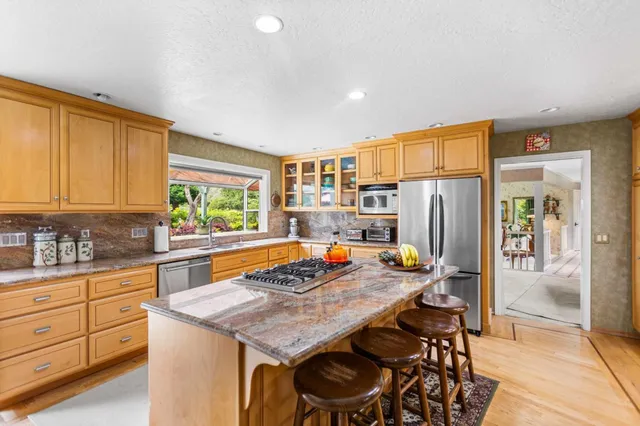 a kitchen with stainless steel appliances granite countertop a table chairs in it and wooden floors