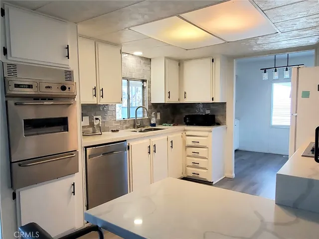 a kitchen with cabinets stainless steel appliances and wooden floor