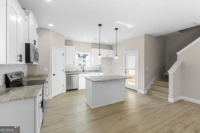 a kitchen with granite countertop a sink cabinets and wooden floor