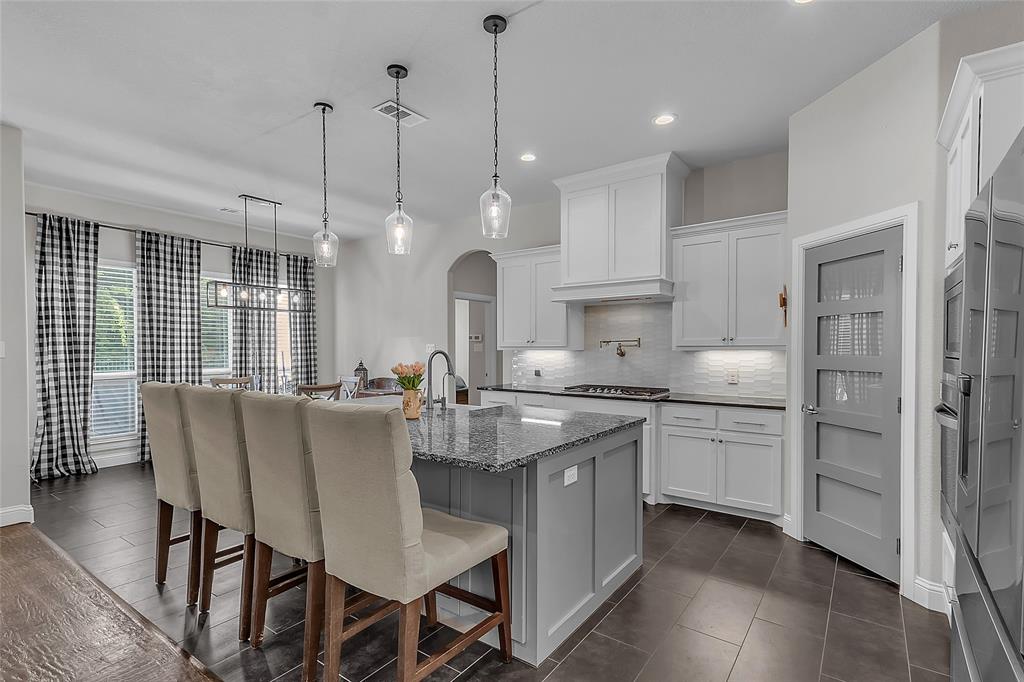 1014 Rennard Street Caddo Mills, TX 75135 - Photo 3 of 39 Kitchen featuring a large island with a granite countertop, shaker-style cabinetry with ample storage, integrated stainless steel appliances, and dark tile flooring