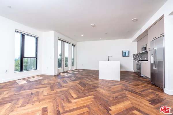 a kitchen with stainless steel appliances a refrigerator a sink a stove and white cabinets