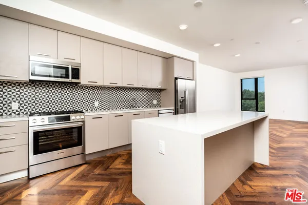 a view of an empty room with a kitchen and a window