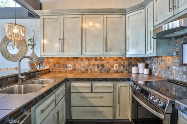 a kitchen with granite countertop a stove a sink dishwasher and cabinets with wooden floor