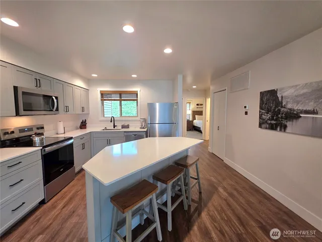 a large kitchen with cabinets wooden floor and stainless steel appliances