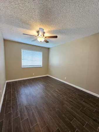 a view of empty room with wooden floor and fan