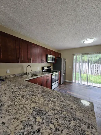 a kitchen with granite countertop wooden cabinets a sink and a stove