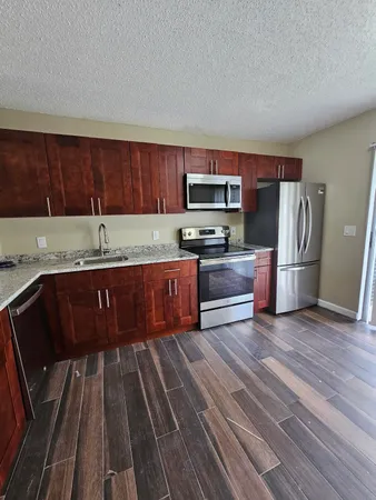 a kitchen with kitchen island granite countertop wooden cabinets a refrigerator and a stove