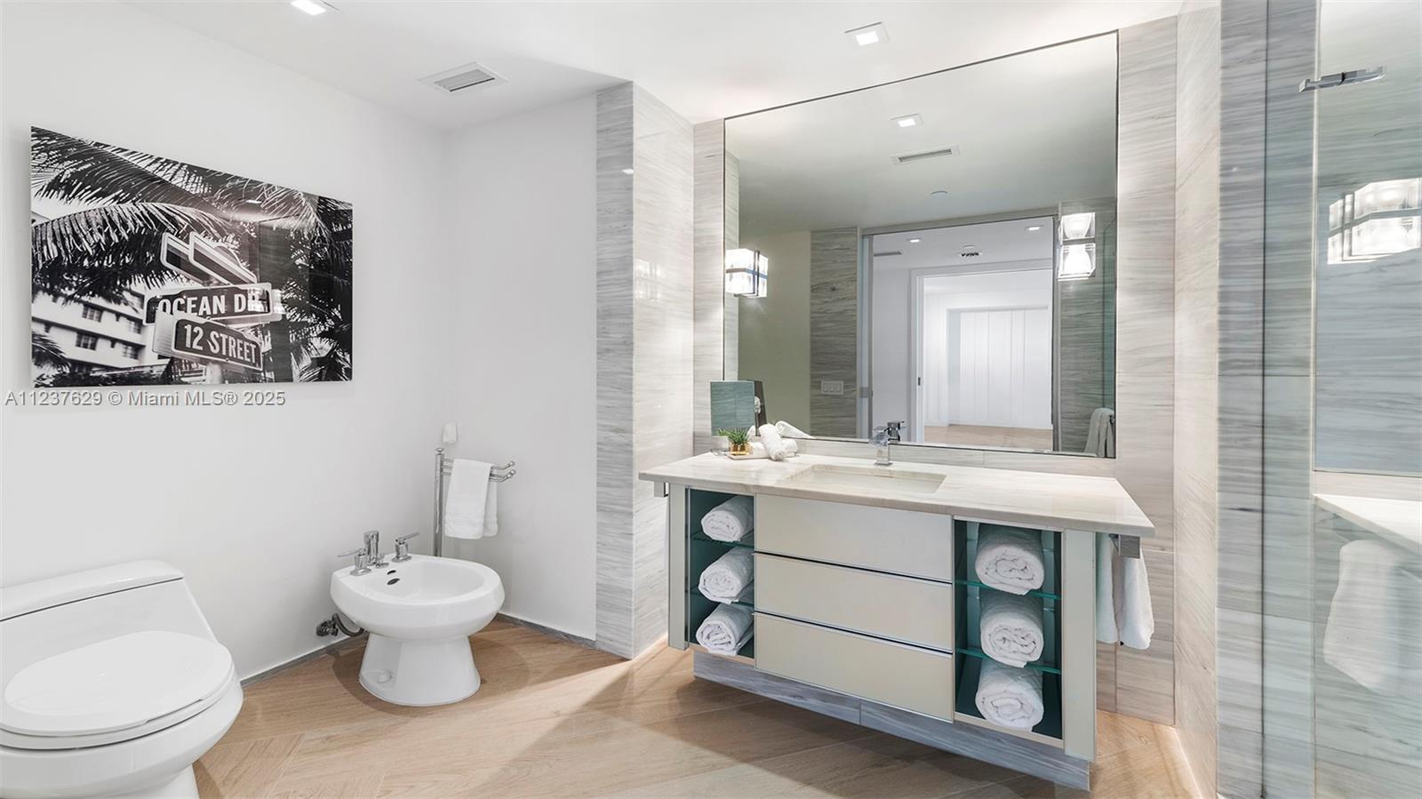2201 Collins Avenue, Unit 804 Miami Beach, FL 33139 - Photo 34 of 41 a spacious bathroom with a toilet sink and mirror