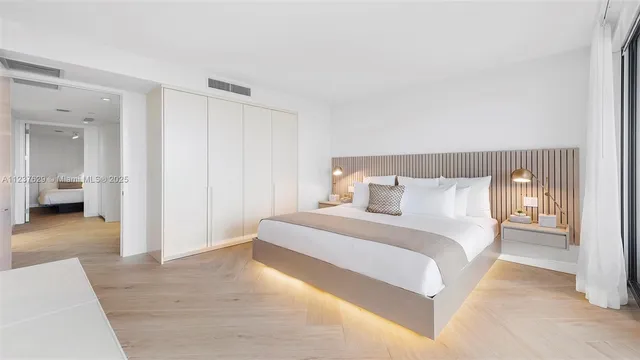 a bedroom with a large bed and a flat tv screen on dresser