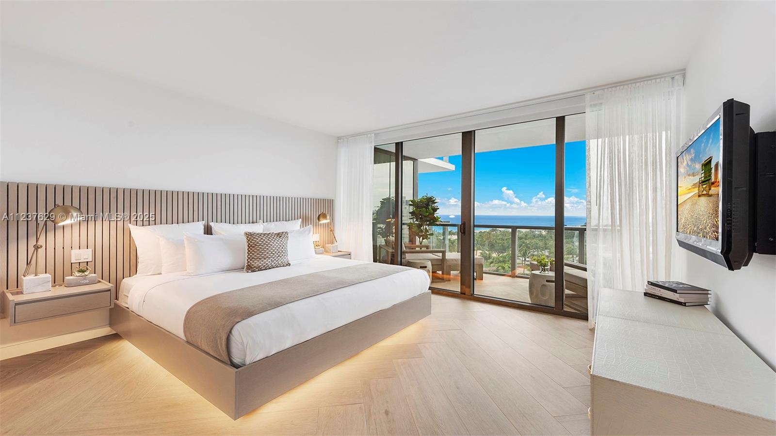 2201 Collins Avenue, Unit 804 Miami Beach, FL 33139 - Photo 37 of 41 a bedroom with a large bed and a flat tv screen on dresser