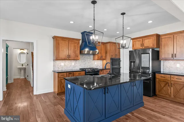 a kitchen with stainless steel appliances granite countertop wooden floors and wooden cabinets