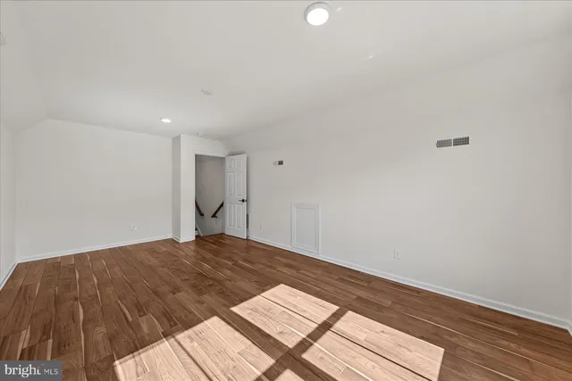 a view of an empty room with wooden floor fireplace and a window