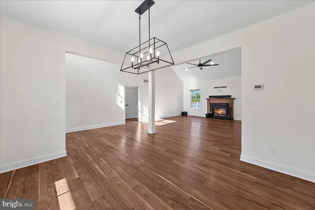a view of empty room with wooden floor fireplace and window