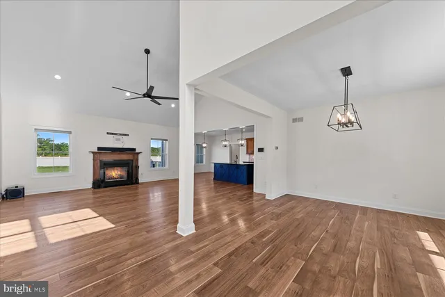 an empty room with wooden floor fireplace and windows